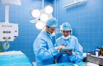 Two Surgeons Looking Over iPad Info in Surgical Room