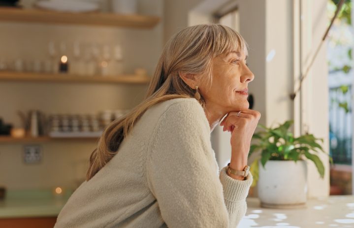 Window, smile and elderly woman with thinking at home for retirement, satisfaction and peace on weekend. Relax, senior person and calm with idea for reflection, mindfulness and good memory in house